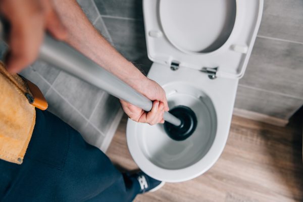 cropped-shot-of-male-plumber-using-plunger-and-cleaning-toilet-in-bathroom plombier 24h belgique